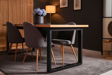 Photo of Wooden table with beautiful flowers and chairs in dining room at night