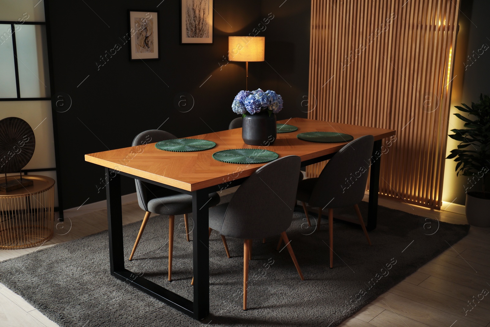 Photo of Wooden table with beautiful flowers and chairs in dining room at night