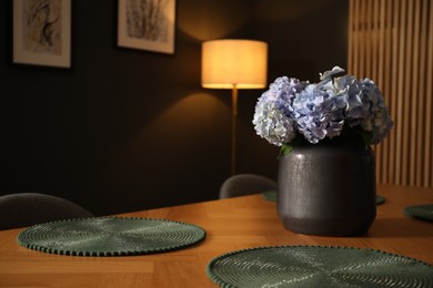 Photo of Beautiful flowers on wooden table in dining at night, closeup