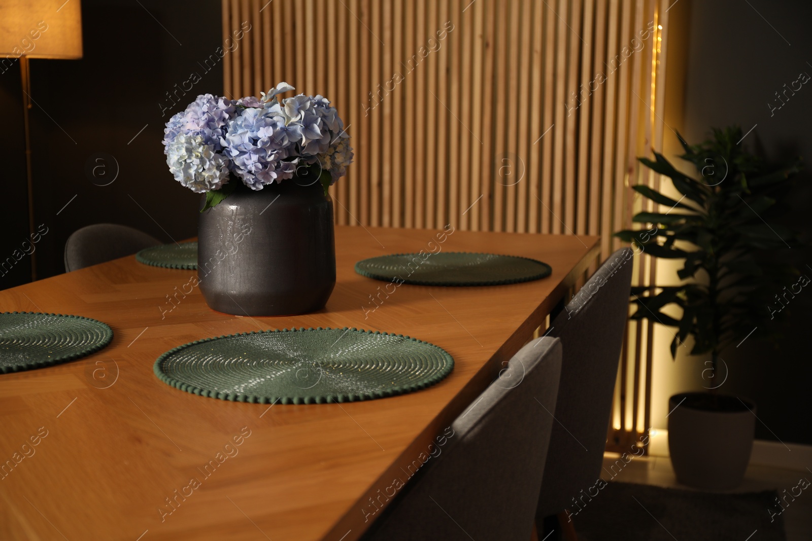 Photo of Beautiful flowers on wooden table in dining at night, closeup