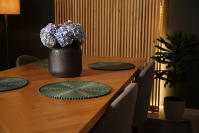 Photo of Beautiful flowers on wooden table in dining at night, closeup