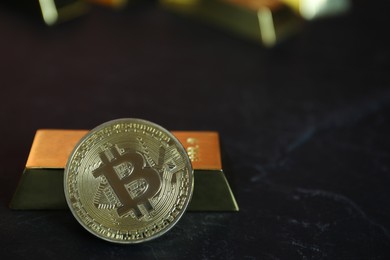 Photo of Cryptocurrency. One golden bitcoin and gold bar on black table, closeup. Space for text