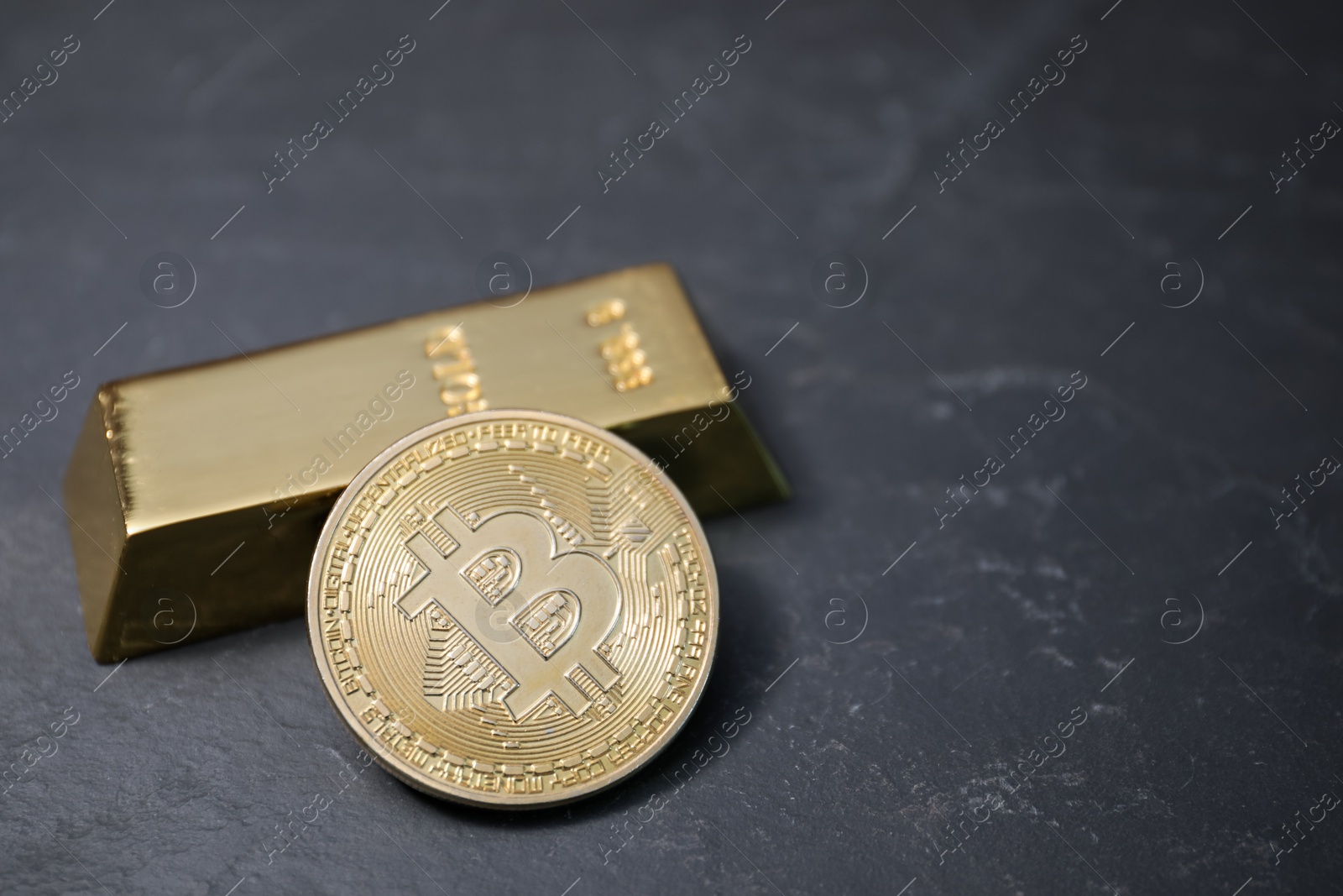 Photo of Cryptocurrency. One golden bitcoin and gold bar on black table, closeup. Space for text