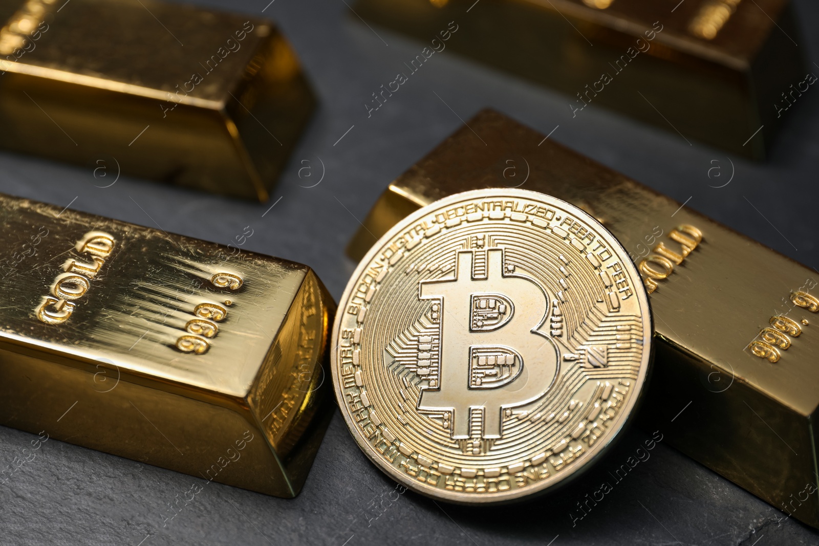 Photo of Cryptocurrency. One golden bitcoin and gold bars on black table, closeup