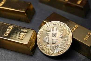 Photo of Cryptocurrency. One golden bitcoin and gold bars on black table, closeup