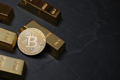Photo of Cryptocurrency. One golden bitcoin and gold bars on black table, above view. Space for text