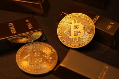 Photo of Cryptocurrency. Golden bitcoins and gold bars on black table, closeup