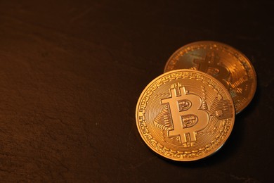 Photo of Cryptocurrency. Golden bitcoin on black table, closeup. Space for text