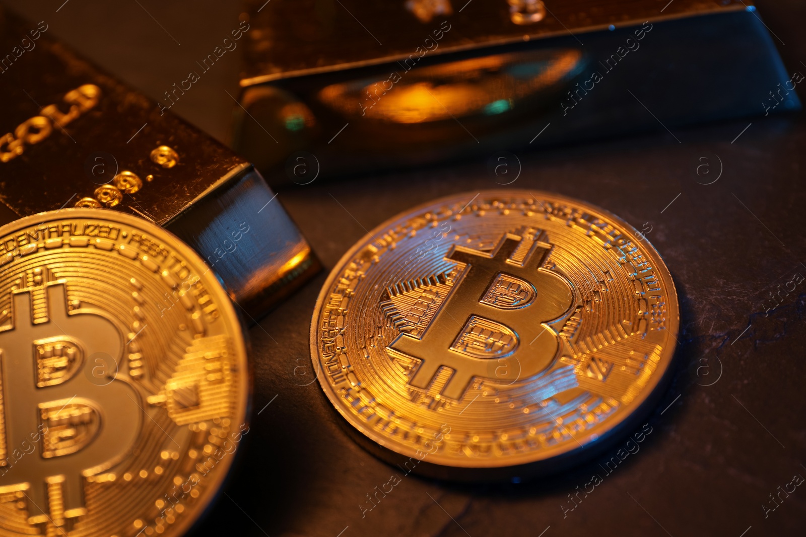 Photo of Cryptocurrency. Golden bitcoins and gold bars on black table, closeup