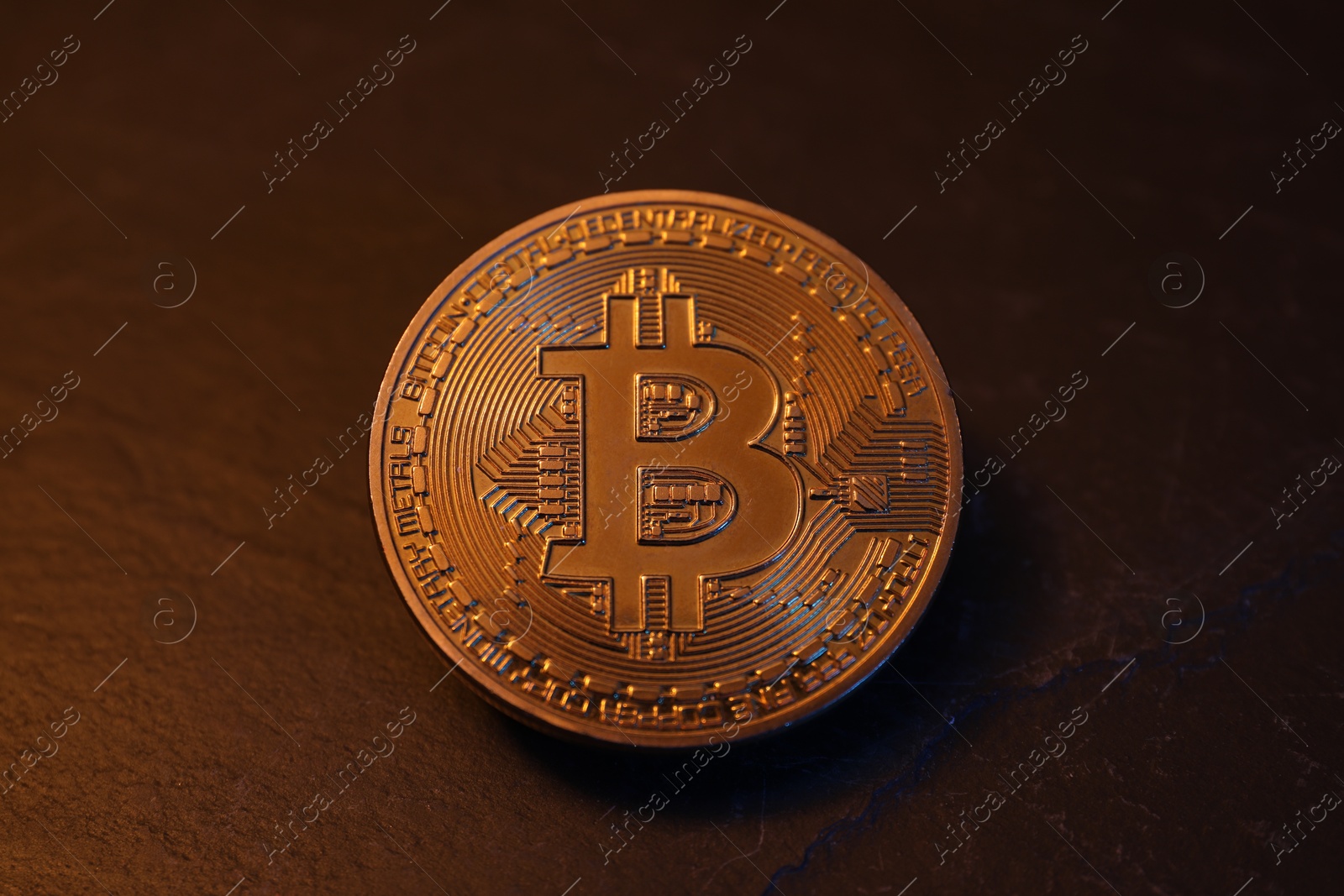 Photo of Cryptocurrency. One golden bitcoin on black table, closeup