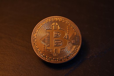 Photo of Cryptocurrency. One golden bitcoin on black table, closeup