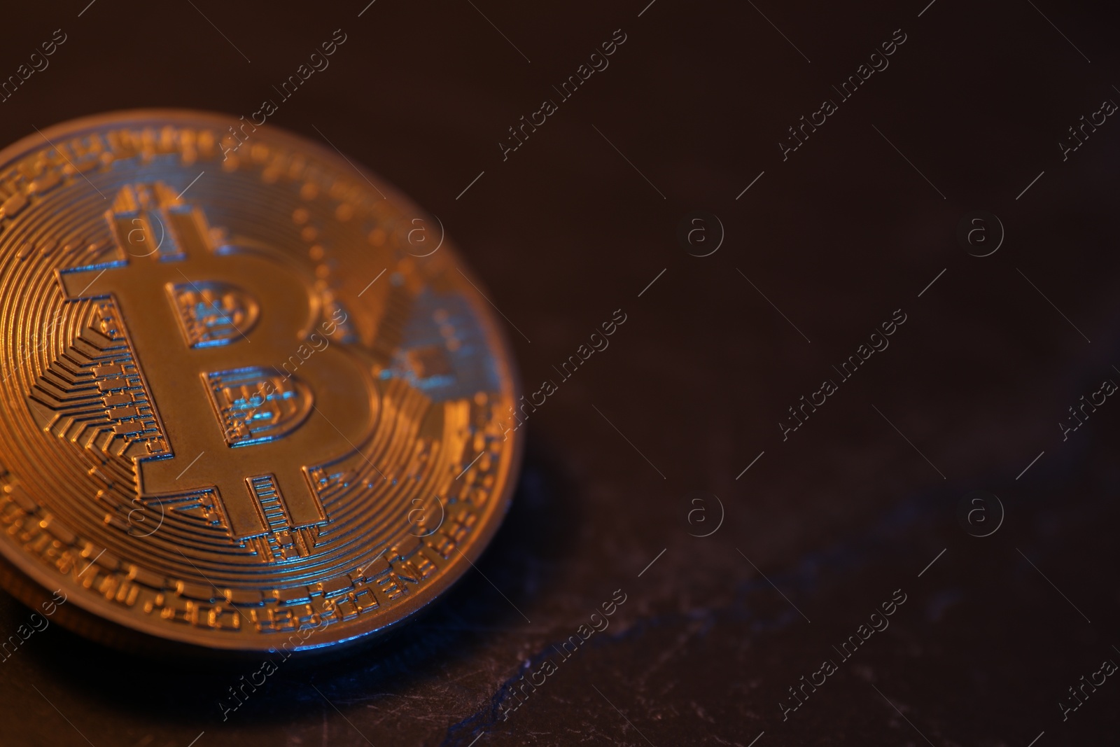 Photo of Cryptocurrency. One golden bitcoin on black table, closeup. Space for text