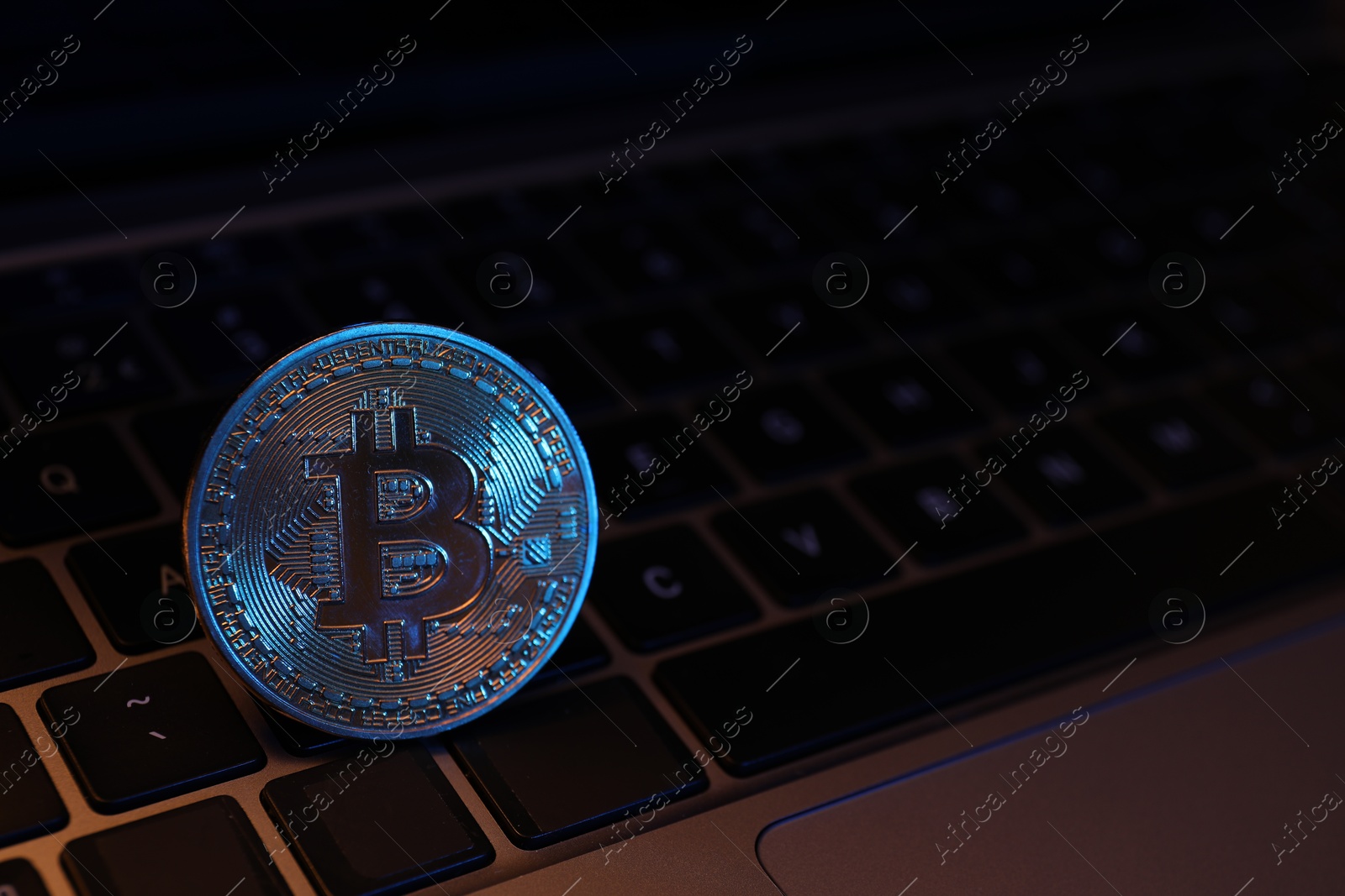 Photo of Cryptocurrency. One silver bitcoin on laptop, closeup. Space for text