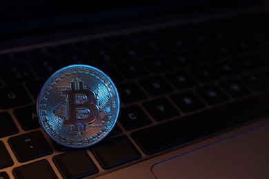 Photo of Cryptocurrency. One silver bitcoin on laptop, closeup. Space for text