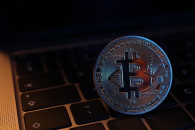 Photo of Cryptocurrency. One silver bitcoin on laptop, closeup. Space for text