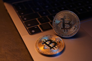 Photo of Cryptocurrency. Silver bitcoins and laptop on black table, closeup. Space for text