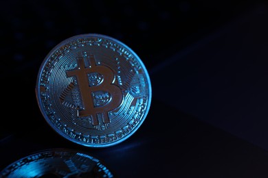 Photo of Cryptocurrency. One silver bitcoin on black mirror surface, closeup. Space for text