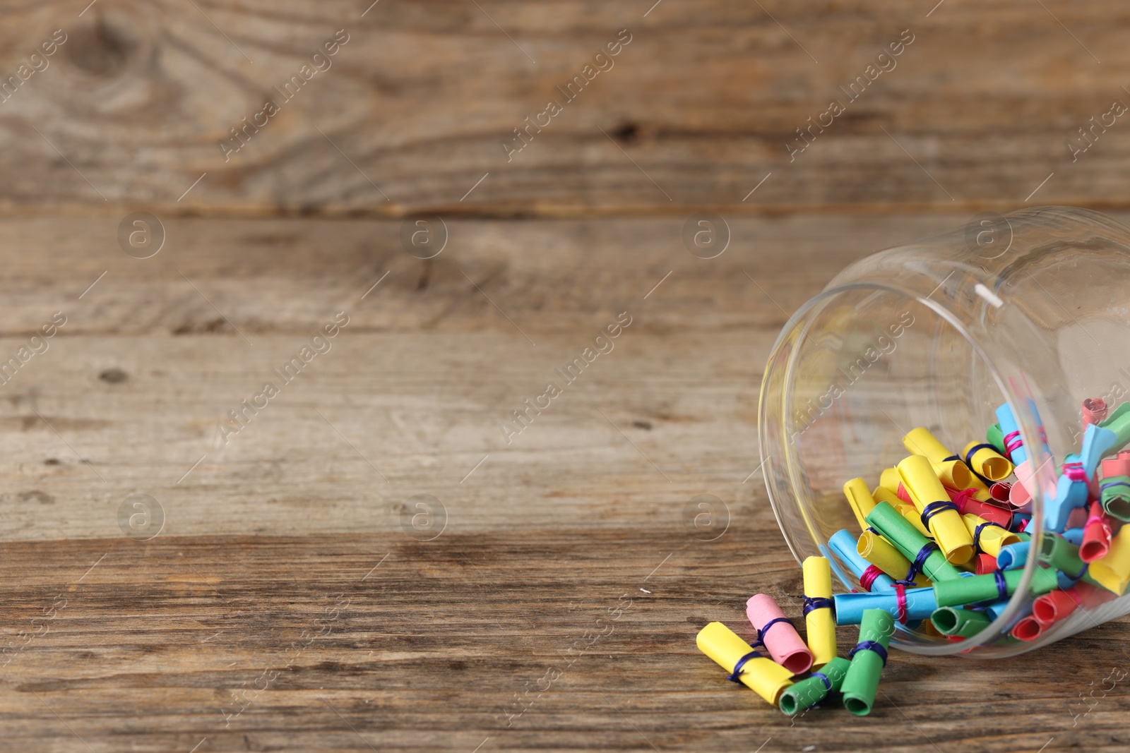 Colorful paper pieces in glass jar on wooden table, closeup. Space for text. Notes with messages Photo of Colorful paper pieces in glass jar on wooden table, closeup. Space for text. Notes with messages
