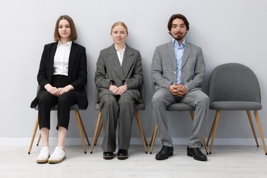 Photo of People waiting in queue on chairs indoors