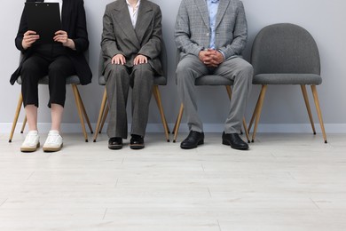 Photo of People waiting in queue on chairs indoors, closeup