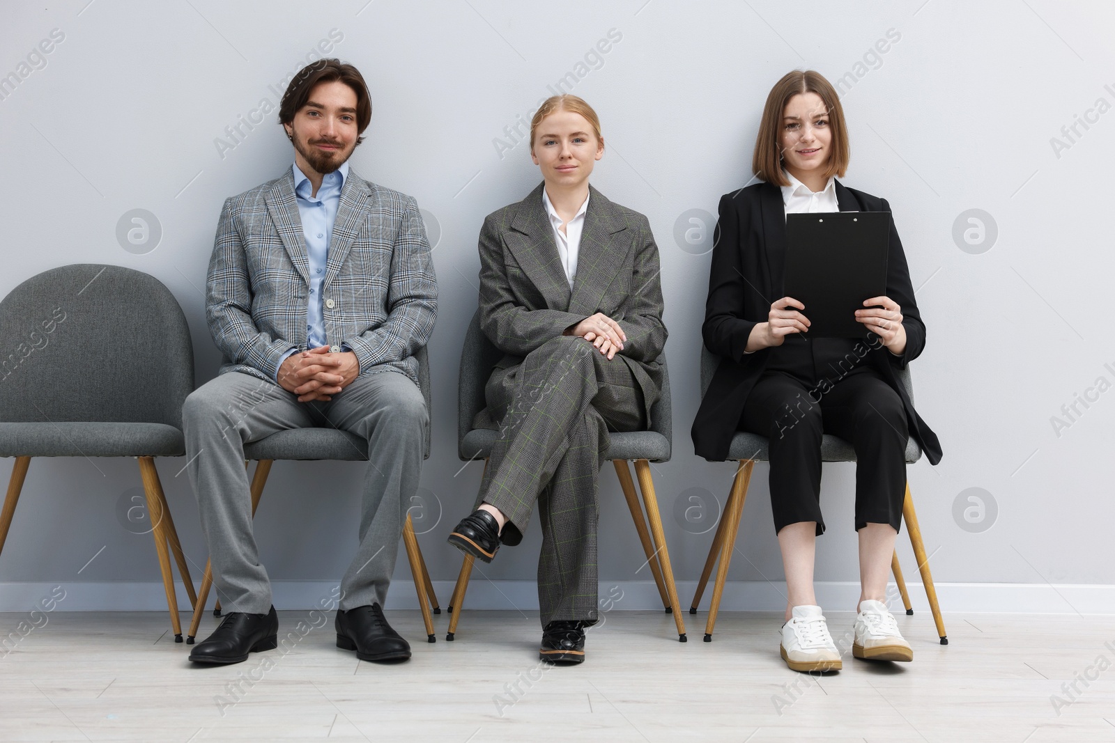 People waiting in queue on chairs indoors Photo of People waiting in queue on chairs indoors