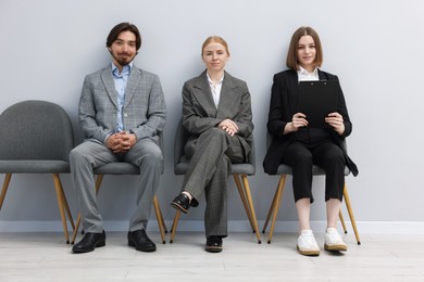 Photo of People waiting in queue on chairs indoors