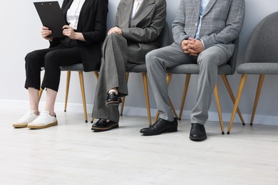 Photo of People waiting in queue on chairs indoors, closeup