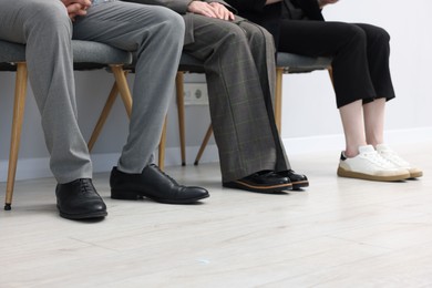 Photo of People waiting in queue on chairs indoors, closeup