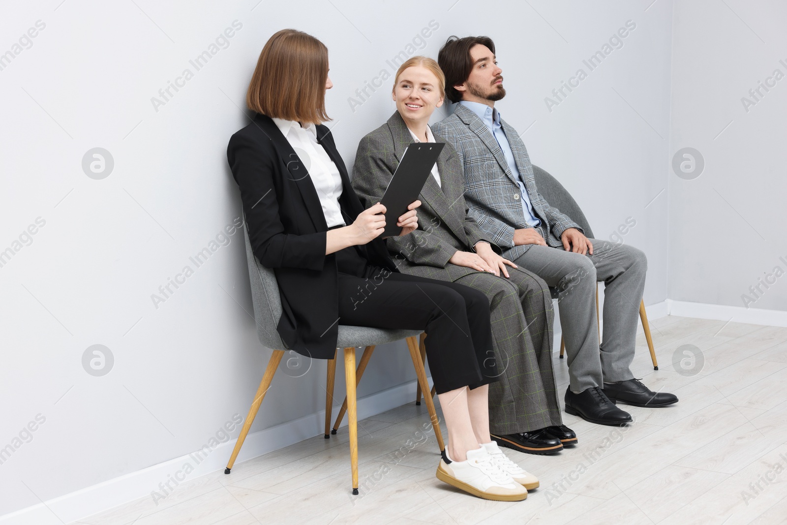 People waiting in queue on chairs indoors Photo of People waiting in queue on chairs indoors