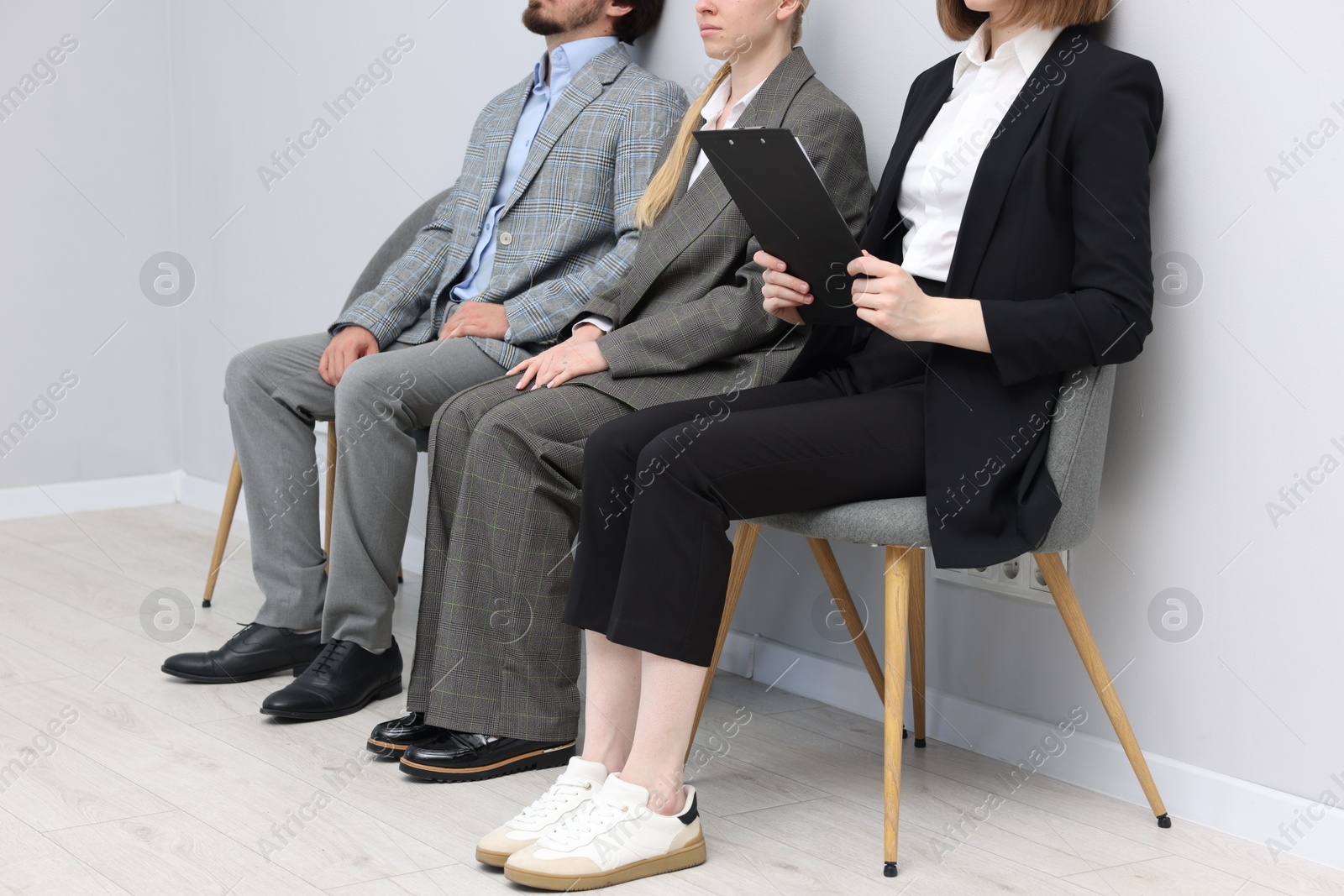 People waiting in queue on chairs indoors, closeup Photo of People waiting in queue on chairs indoors, closeup