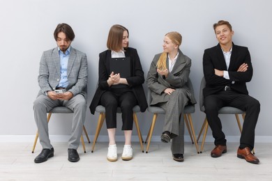 Photo of People waiting in queue on chairs indoors