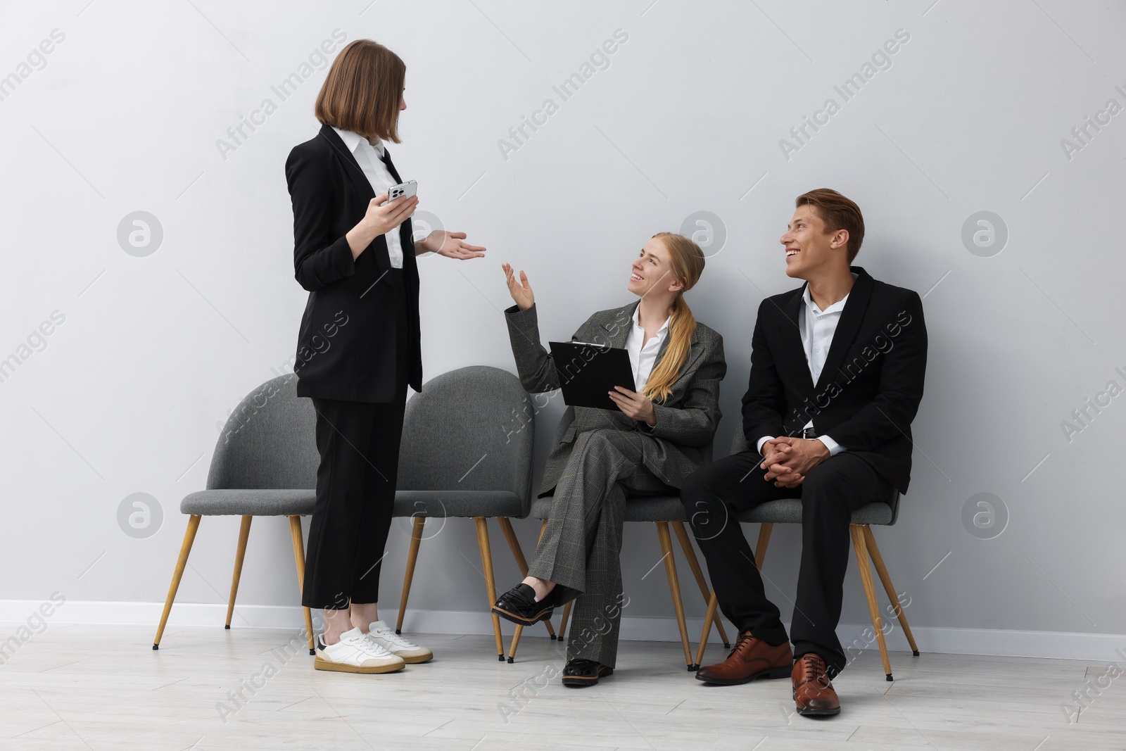 People waiting in queue on chairs indoors Photo of People waiting in queue on chairs indoors