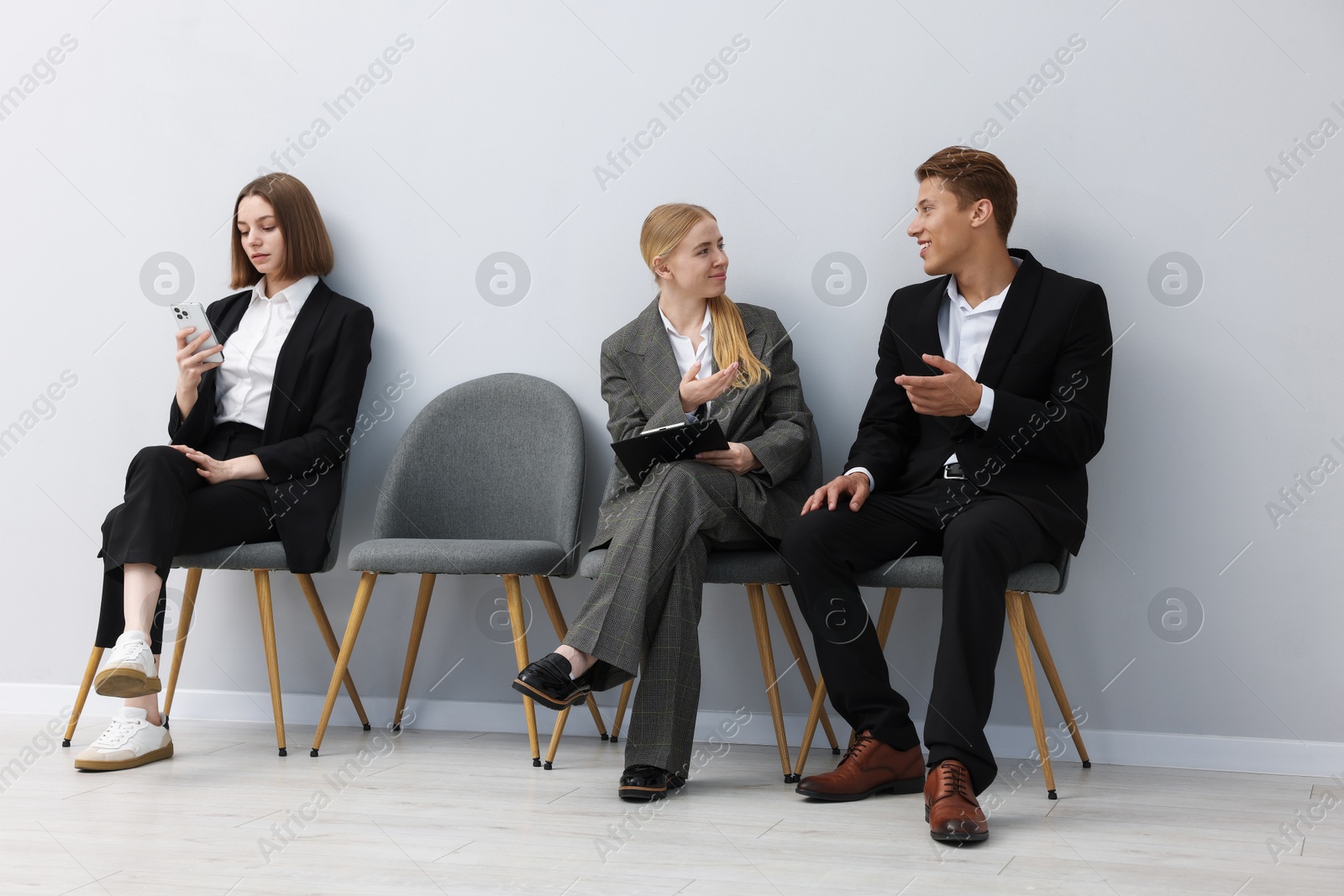 People waiting in queue on chairs indoors Photo of People waiting in queue on chairs indoors