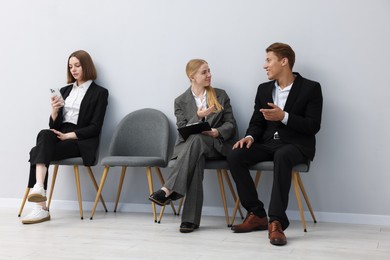 Photo of People waiting in queue on chairs indoors