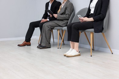 Photo of People waiting in queue on chairs indoors, closeup