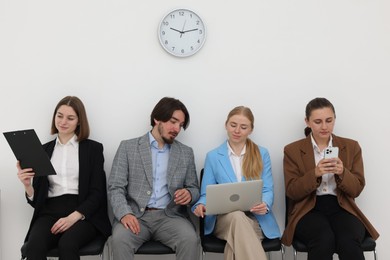 Photo of People waiting in queue on chairs indoors