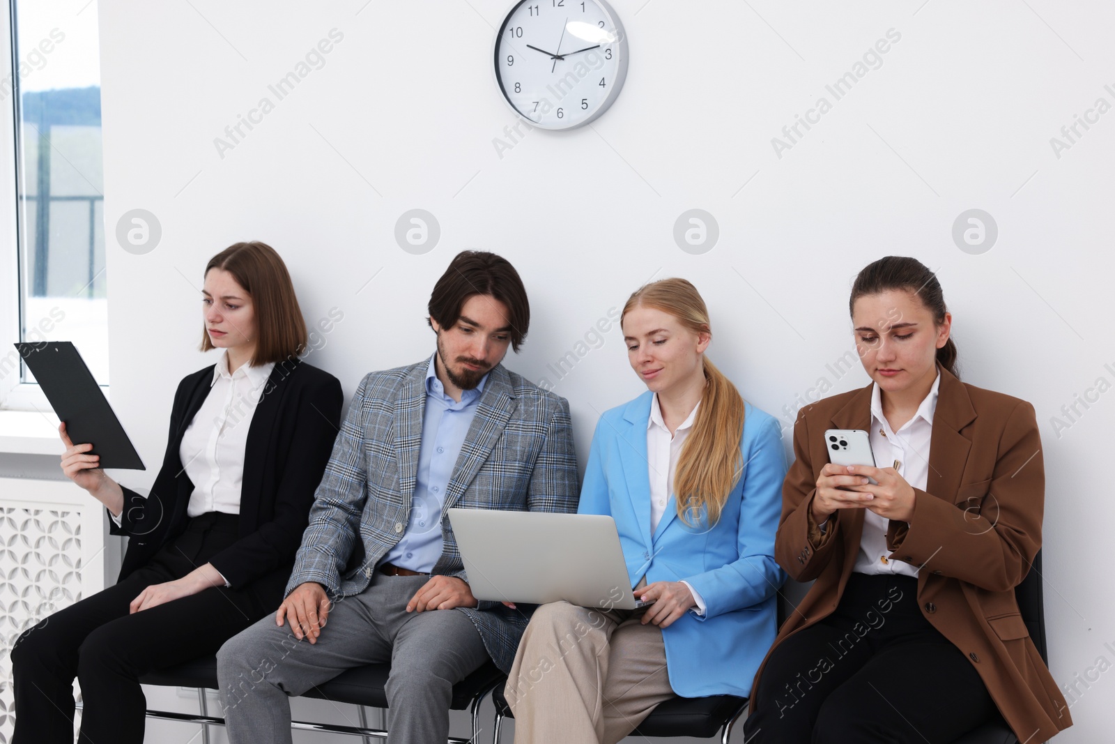 People waiting in queue on chairs indoors Photo of People waiting in queue on chairs indoors