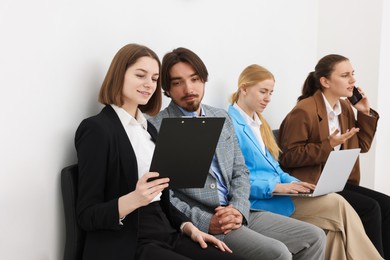 Photo of People waiting in queue on chairs indoors