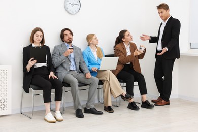Photo of People waiting in queue on chairs indoors