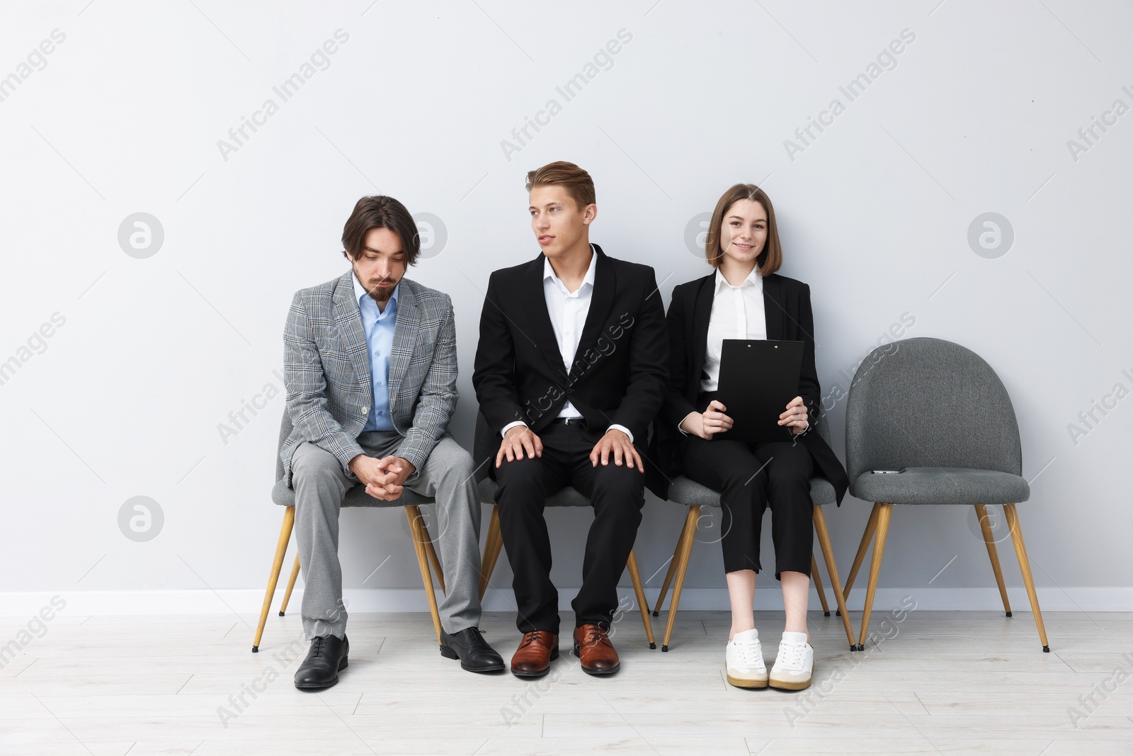 People waiting in queue on chairs indoors Photo of People waiting in queue on chairs indoors