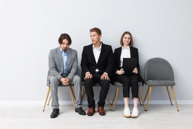Photo of People waiting in queue on chairs indoors