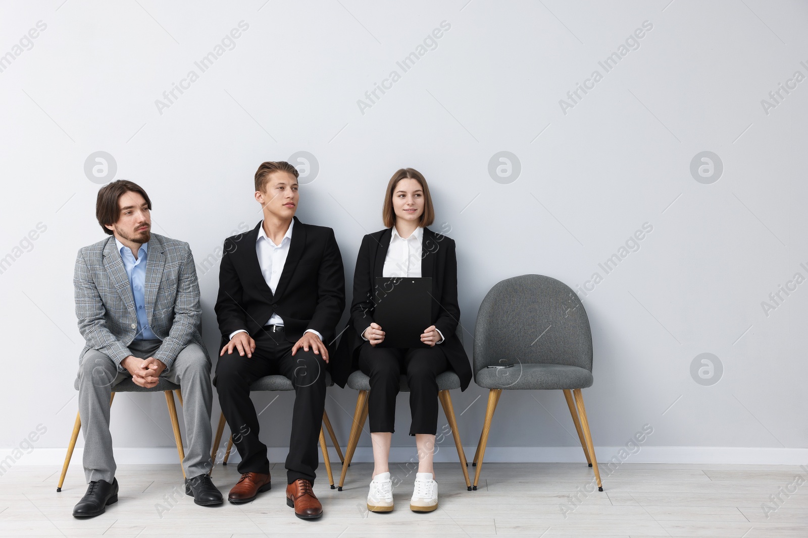 People waiting in queue on chairs indoors Photo of People waiting in queue on chairs indoors