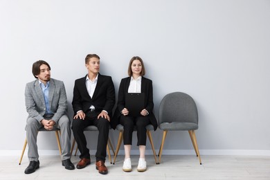 Photo of People waiting in queue on chairs indoors