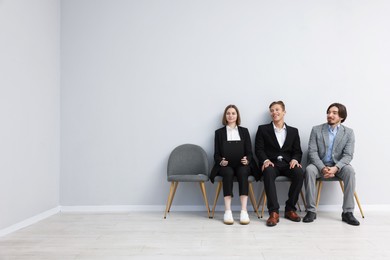 Photo of People waiting in queue on chairs indoors