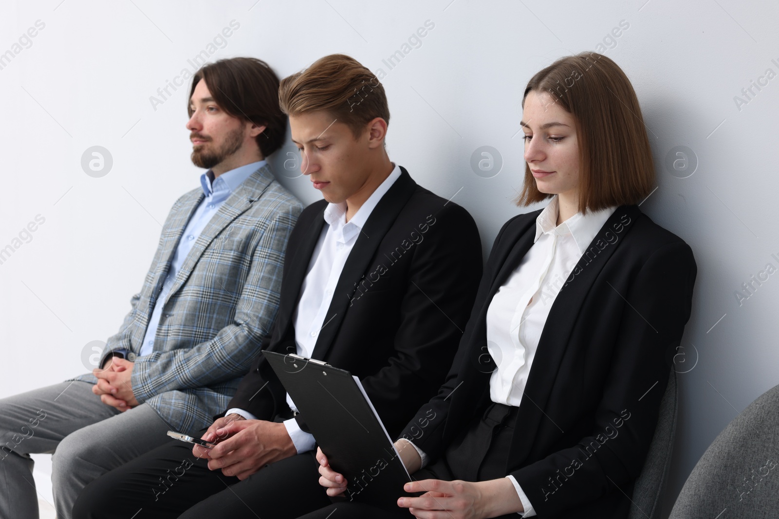People waiting in queue on chairs indoors Photo of People waiting in queue on chairs indoors