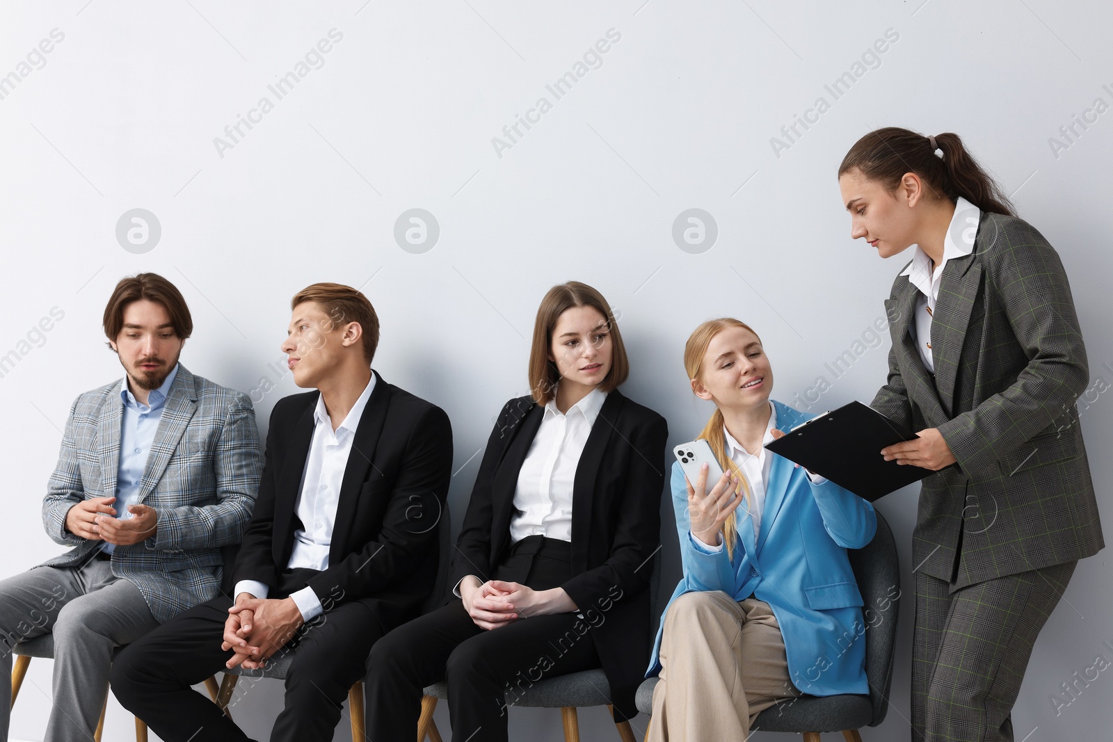 People waiting in queue on chairs indoors Photo of People waiting in queue on chairs indoors