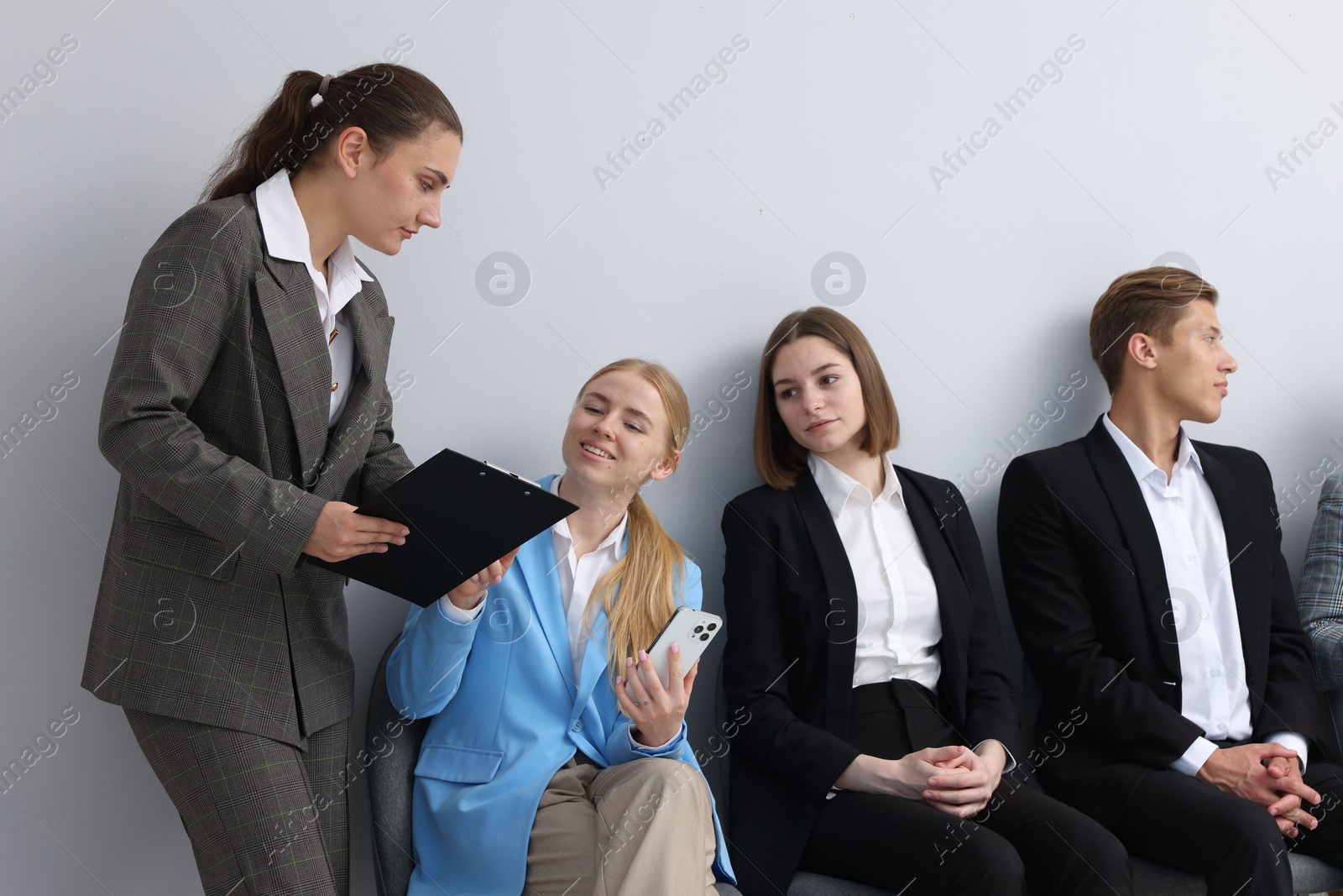 People waiting in queue on chairs indoors Photo of People waiting in queue on chairs indoors