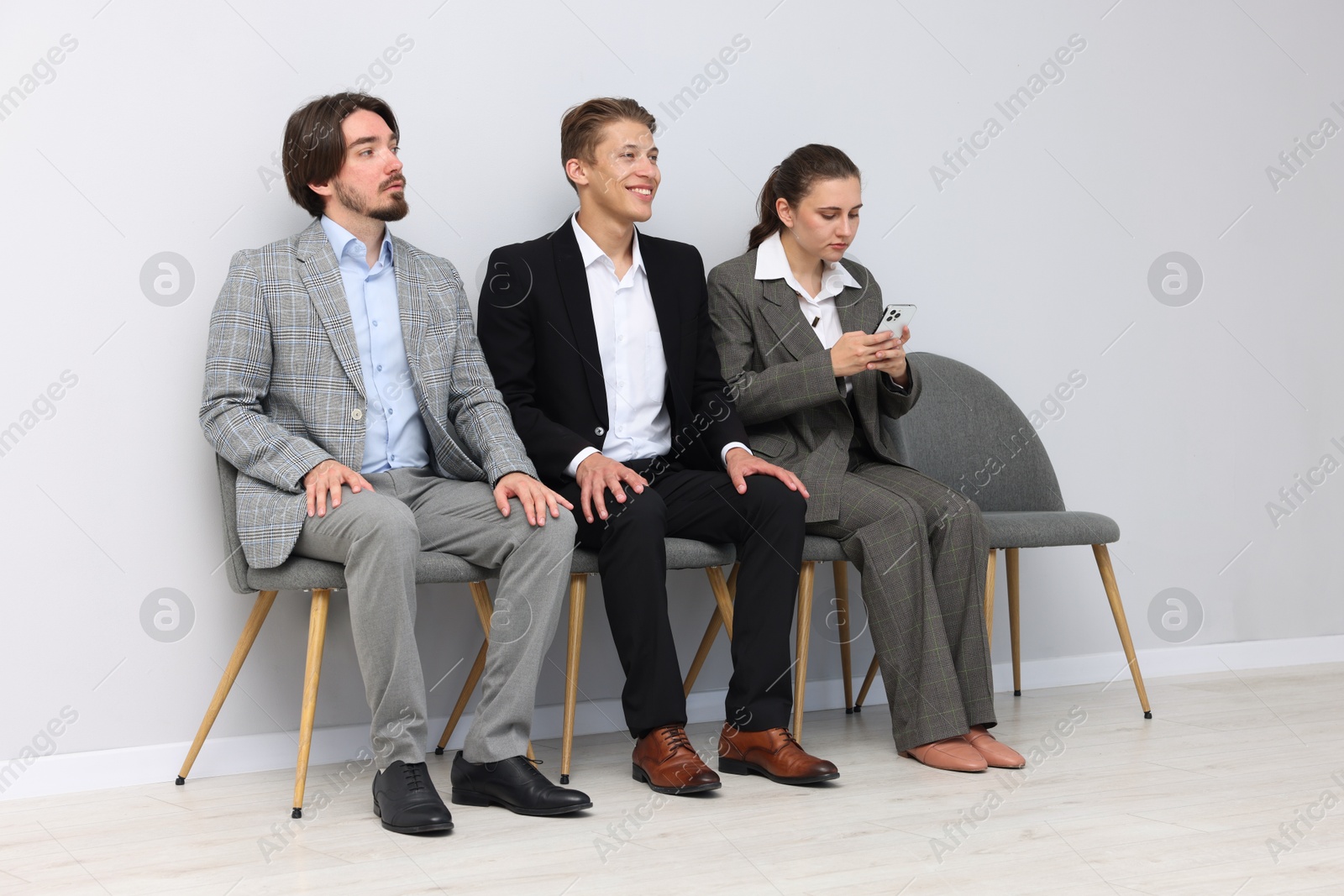 People waiting in queue on chairs indoors Photo of People waiting in queue on chairs indoors