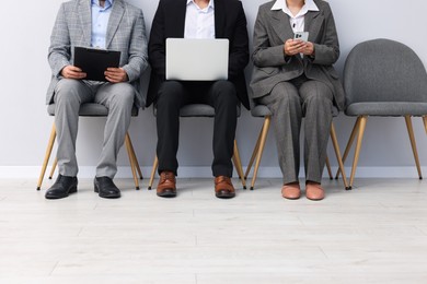 Photo of People waiting in queue on chairs indoors, closeup
