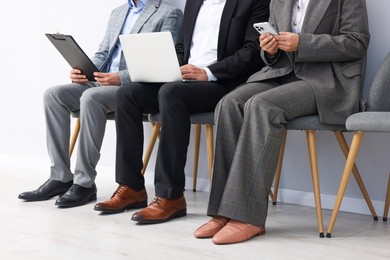 Photo of People waiting in queue on chairs indoors, closeup
